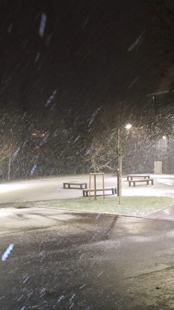 Vier Bänke unter einer Laterne im Schneesturm.